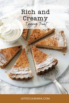 Slices of creamy eggnog tart dusted with powdered sugar, arranged on a plate with a dollop of whipped cream in a small bowl.