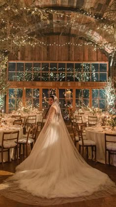 a bride and groom are standing in front of their wedding reception tables at the barn