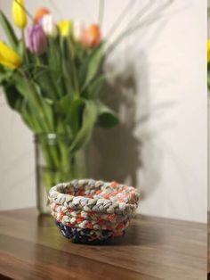 a bowl sitting on top of a wooden table next to a vase filled with flowers