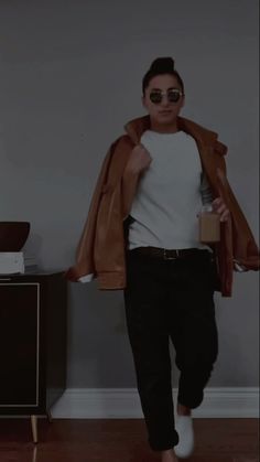 a man wearing sunglasses and a jacket is walking through the room with his hands in his pockets