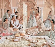 a group of people standing around each other in front of a table filled with food