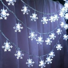 snowflake lights are hanging from a curtain