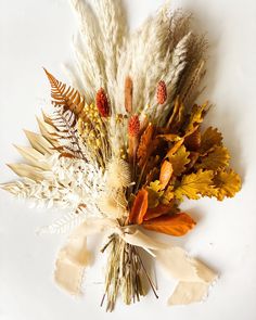 an arrangement of dried flowers and leaves on a white background