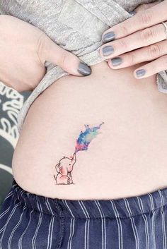 a woman's stomach with a small elephant tattoo on the side of her belly