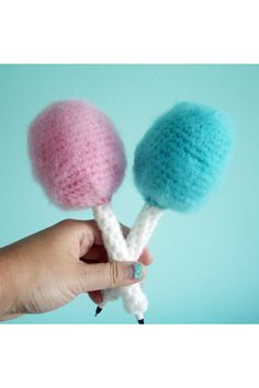 two crocheted cotton candy lollipops being held by a person's hand