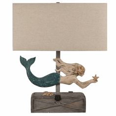 a lamp with a mermaid on it and a wooden box underneath the lamp shade,