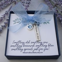 a key with a blue ribbon on it in a box next to some lavender flowers