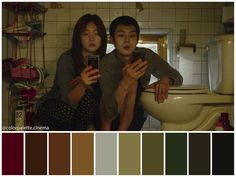 two people sitting on a toilet looking at their cell phones with color swatches in front of them