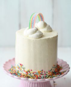 a cake on a pink plate with sprinkles and a rainbow topper