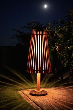 a lamp sitting on top of a wooden table next to a tree in the dark