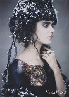 a woman in a black dress with white flowers on her head, wearing a ring