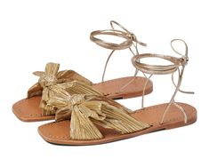 a pair of gold sandals with bows on them