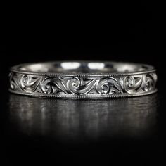 an ornate wedding band with filigrees and scrolls on the sides, in white gold