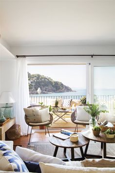 a living room filled with furniture and a large window overlooking the ocean in front of it