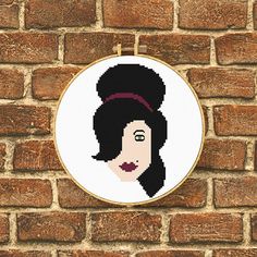 a cross stitch portrait of a woman on a brick wall