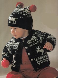 a baby wearing a black and white knitted coat, red pants, and hat