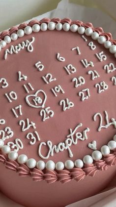 a pink cake with white frosting and numbers on it