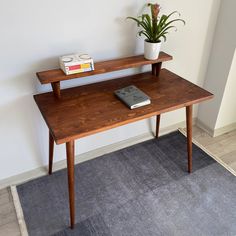 a small wooden table with a book and potted plant on top