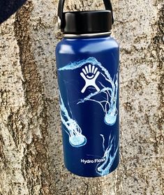 a blue water bottle is hanging on a tree trunk with an image of fish in the water