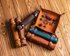 three leather dice holders on top of a wooden table with dice markers in the pouch