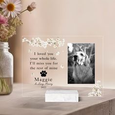 a glass photo frame with a dog's paw on it and flowers in the background