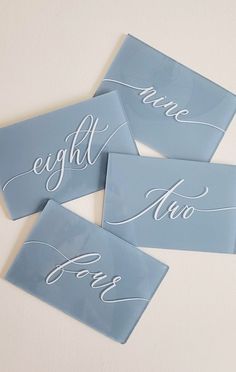 three blue glass coasters with white calligraphy on them