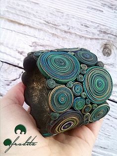 a hand holding a rock with spirals on it