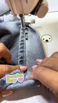 someone using a sewing machine to sew a button on a pair of blue jeans