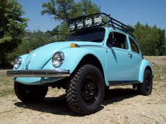 an old blue volkswagen beetle is parked in the dirt