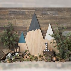 there is a wooden mountain with trees and candles on the mantle next to it, along with other decorations