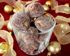 powdered sugar covered donuts in a glass bowl on a red tablecloth with gold ornaments