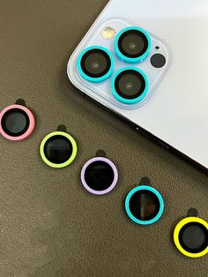 four cell phones are sitting on the table next to each other with different colored circles around them