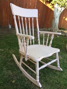 a white rocking chair sitting in the grass