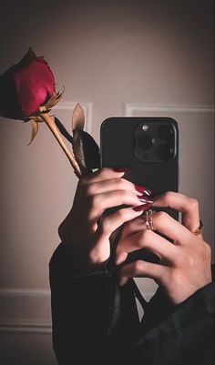 a woman taking a selfie with her phone and holding a rose in front of her face