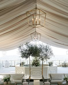 an outdoor venue with tables and chairs under a tented area that has white drapes on it