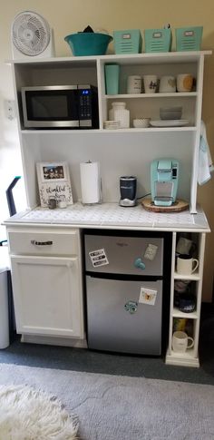 a kitchen area with refrigerator, microwave and shelves