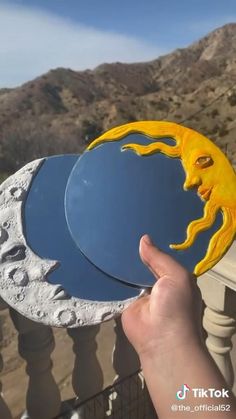 a hand is holding two plates with the moon and man's face on them