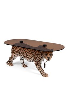 a cheetah table with a glass top and leopard legs on the bottom, standing in front of a white background