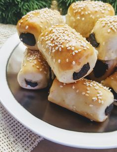 a white plate topped with rolls covered in sesame seeds