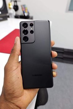 someone is holding up their new samsung note 20 pro in front of the computer desk