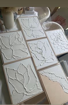 some white tiles sitting on top of a table next to a cup and vase with flowers