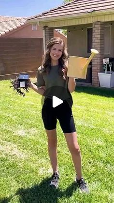 a woman holding a kite in her hand and standing on the grass with it's wings