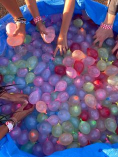 several people are playing with balloons in a blue plastic pool that is filled with water