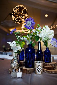 blue vases with white and purple flowers are sitting on a table in a banquet hall