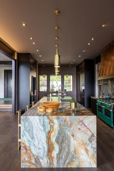 a large kitchen with marble counter tops and gold accents on the island in front of an open floor plan