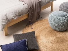 a bed with two pillows on top of it next to a rug and a pillow