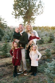 a family standing in the middle of a christmas tree farm posing for a photo with their two children