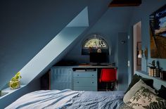 an attic bedroom with blue walls and white bedding