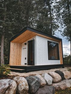 a tiny cabin in the middle of some rocks and trees, with its door open