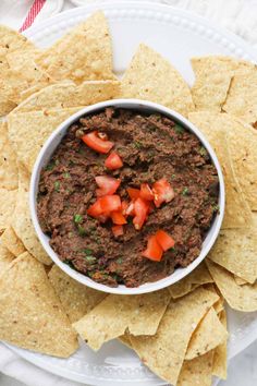 a white bowl filled with salsa surrounded by tortilla chips